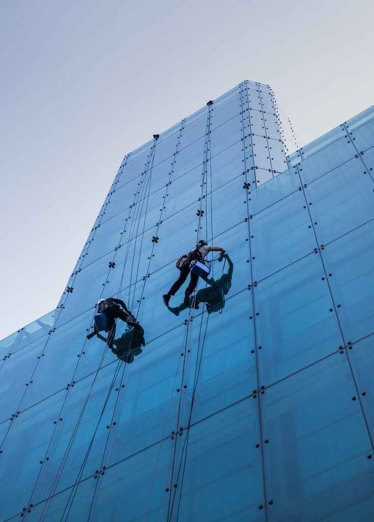Vertical Low Angle Shot Two People Climbing Tall Glass Building Day Time 734x1024
